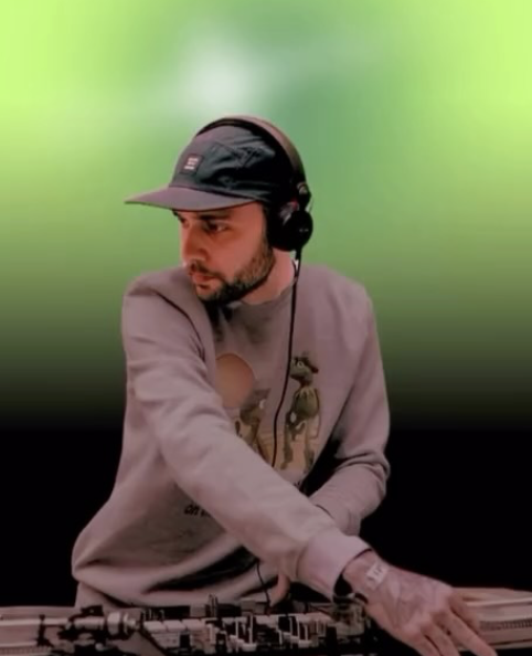 DJ TRUSTORY in a cap and headphones at the decks, from his supplied photograph